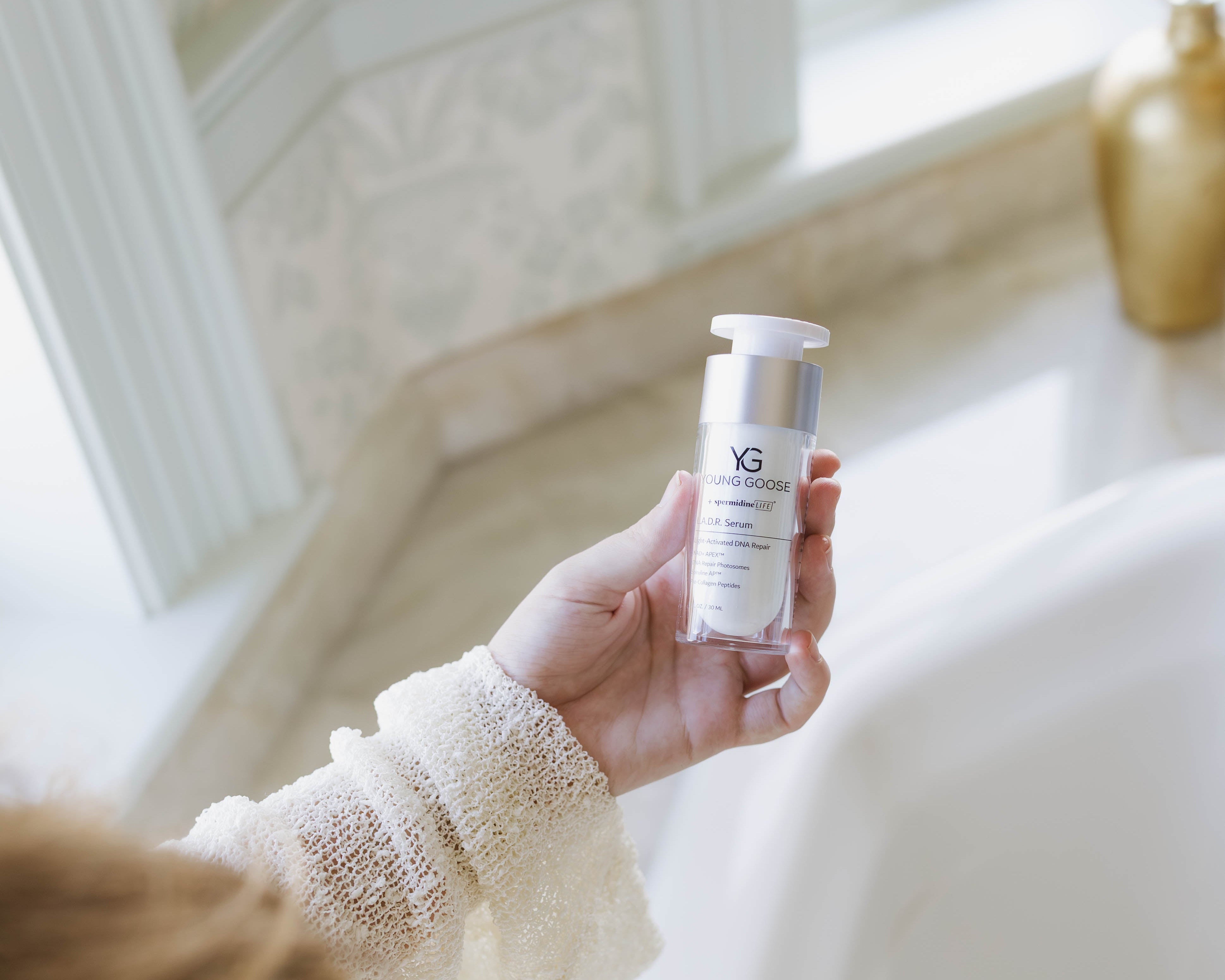 Person holding a skincare bottle in a softly lit room