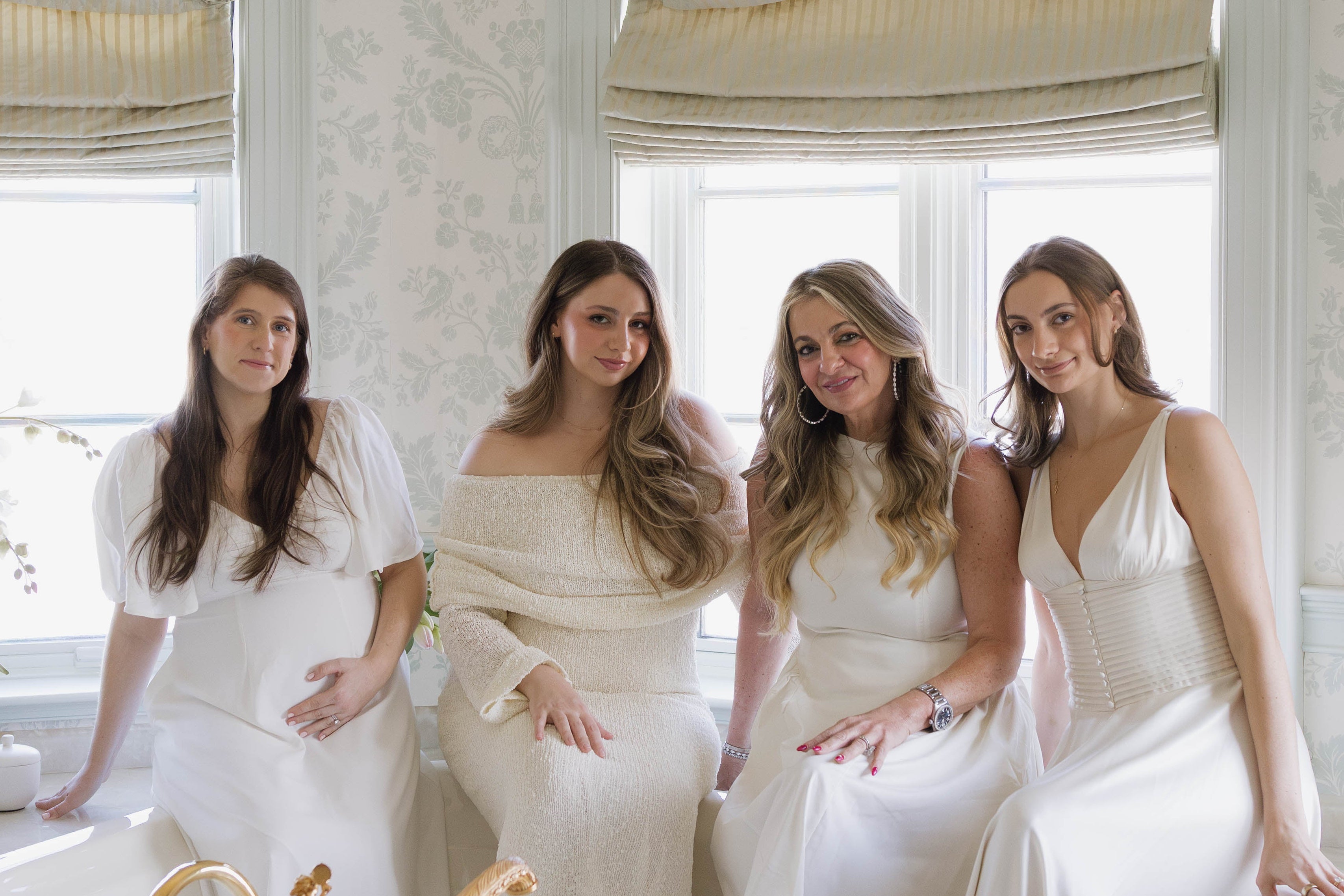 Four women in white dresses standing in a bathroom with decorative elements.