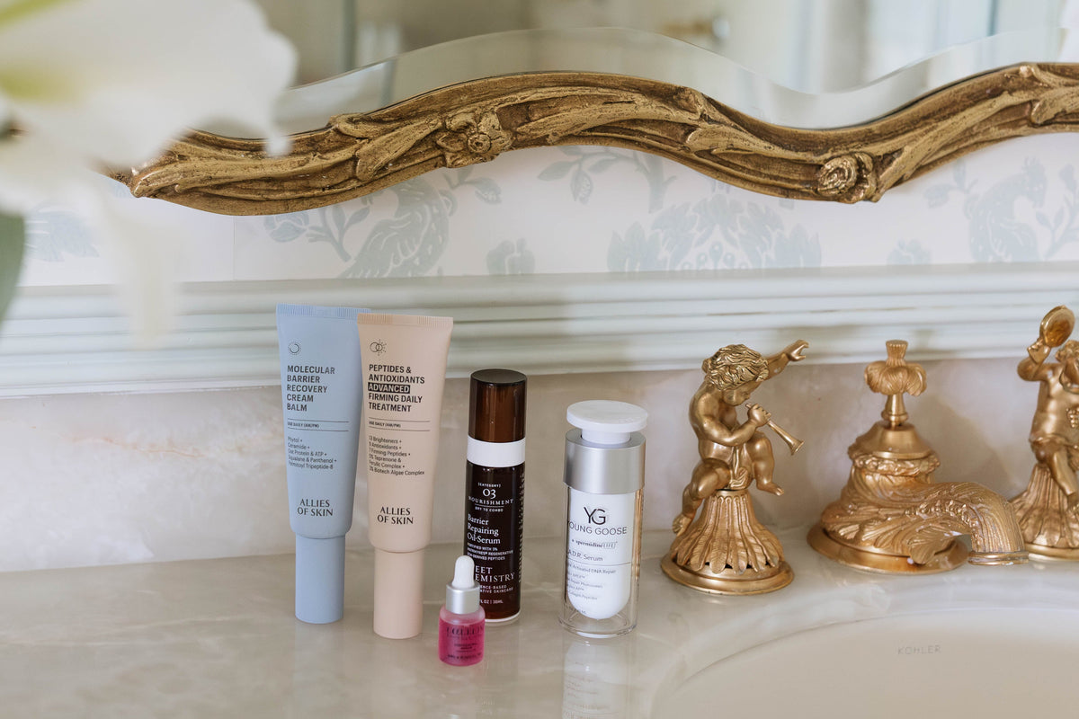 Bathroom counter with skincare products and a decorative mirror.